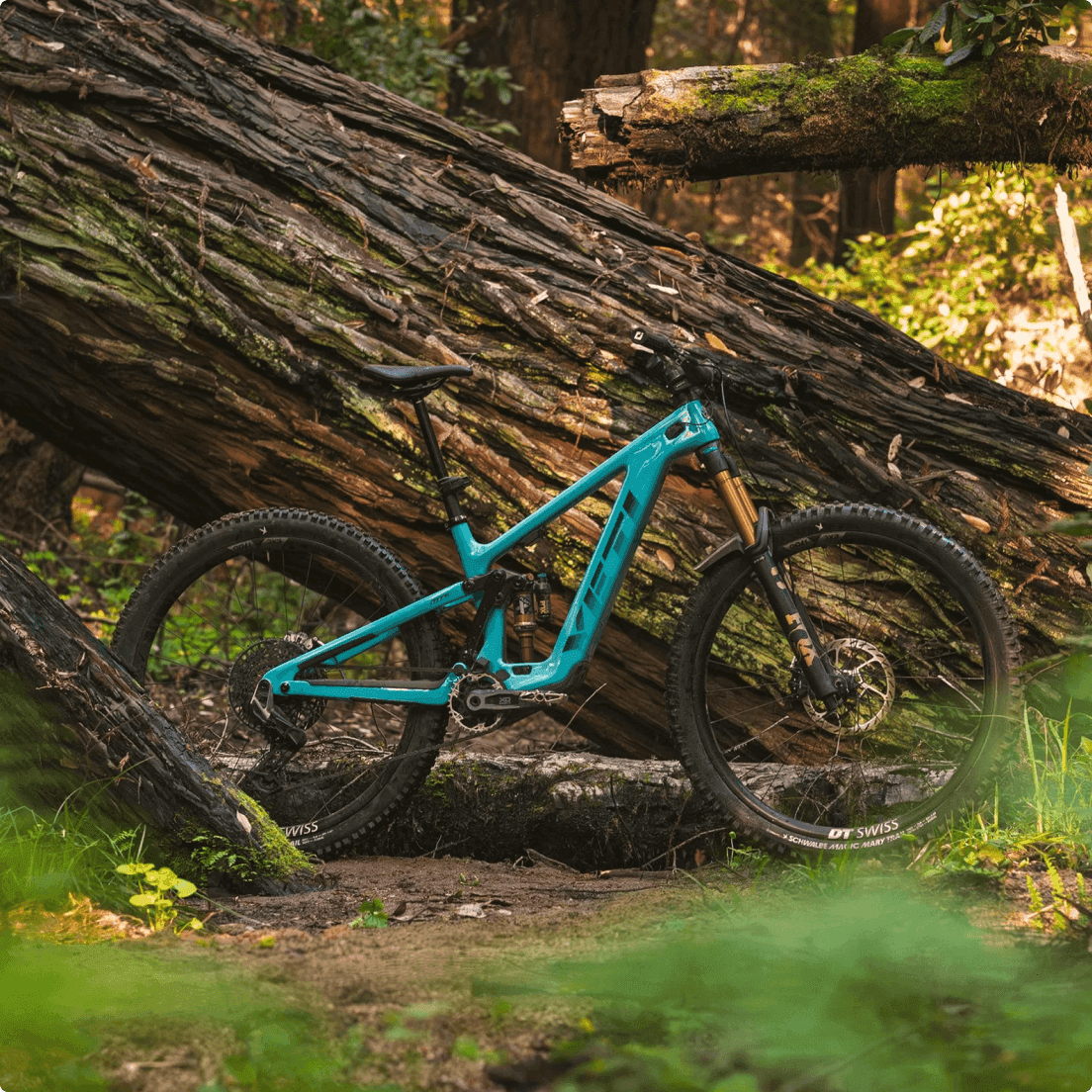 Yeti Cycles turquoise full-suspension mountainbike met DT Swiss wielen op een modderig bospad